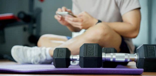 dumbbell-floor-with-man-sitting-using-smartphone Online coaching with smartphone